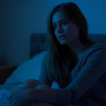 Pessoa acordada durante a madrugada em quarto escuro com iluminação suave.