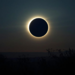 Eclipse solar parcialmente visível no céu com halo de luz e atmosfera contemplativa