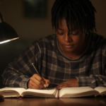 Pessoa estudando em uma mesa com livros e caderno em ambiente tranquilo de aprendizado